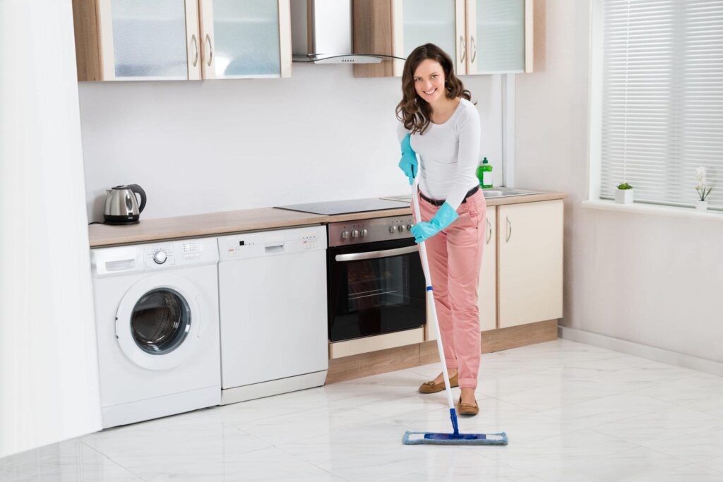 44592034 happy woman cleaning floor with mop in kitchen at home